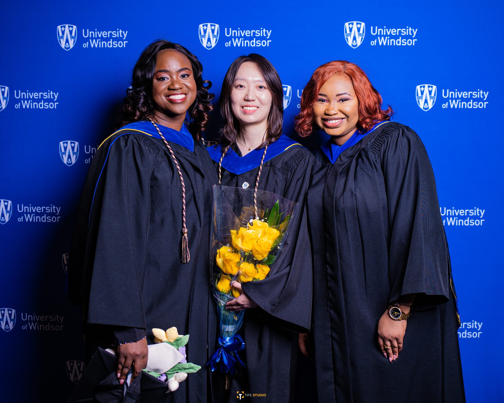 Three graduates at university backdrop